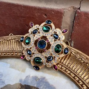 Detailed close-up of a vintage Baroque brooch with colorful crystals and gold-tone finish.