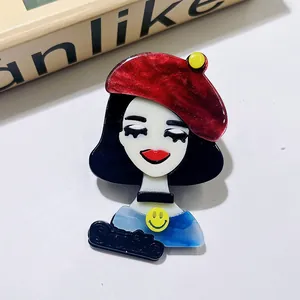 Vue détaillée d'une broche en acrylique avec une fille cartoon et un béret rouge vif.