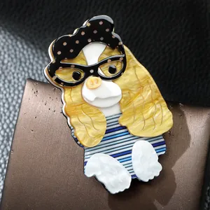 Gros plan d'une broche en acrylique faite main en forme de chien avec lunettes.