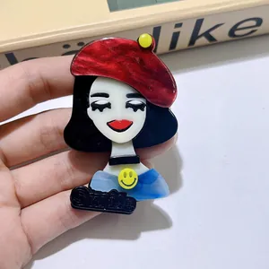 Vue détaillée d'une broche tendance en acrylique représentant une fille avec béret rouge.