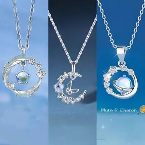 Detailansicht von drei eleganten Silberhalsketten mit Feder-, Mond- und Planetenanhängern.