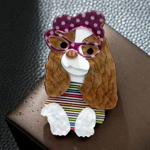 Vue détaillée d'une broche en acrylique faite main en forme de chien avec lunettes.