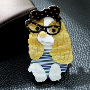Vue détaillée d'une broche en acrylique faite à la main, chien avec lunettes et chemise.