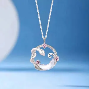Detail of a silver circular necklace with snake and moon charms and pink stones