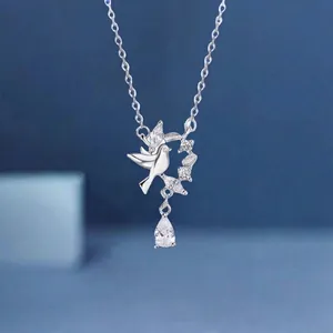 Detailed view of silver bird necklace with flower wreath and pear-shaped crystal drop