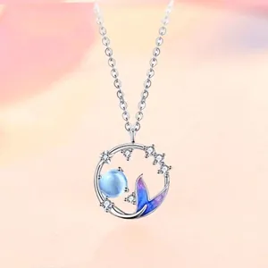 Mermaid tail necklace with a blue bead and star crystals on a soft pink background