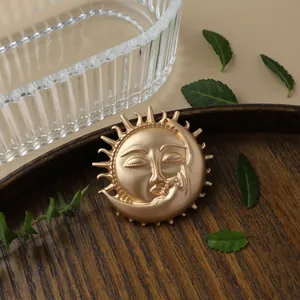 Close-up of vintage matte gold brooch featuring celestial sun and moon design