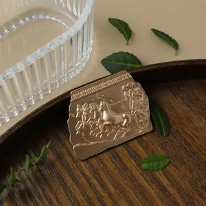 Detailed close-up of a vintage matte gold metal brooch with embossed chariot design