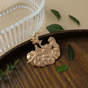 Detail shot of a vintage matte gold fairy and moon brooch on a dark wooden tray