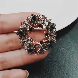 Elegante broche circular con diamantes de imitación coloridos y libélulas detalle