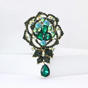 Detailed view of luxury alloy rose brooch with green crystals and waterdrop pendant