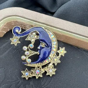 Detailaufnahme einer Vintage-Brosche mit blauem Emaille-Mond, Sternen und Strasssteinen