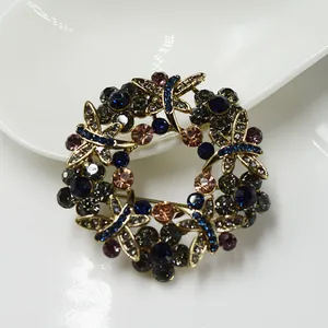 Detalle de broche circular dorado con pedrería azul y motivos de libélulas vintage