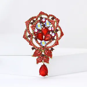 Detailed view of luxury rose brooch with red rhinestones and teardrop pendant.