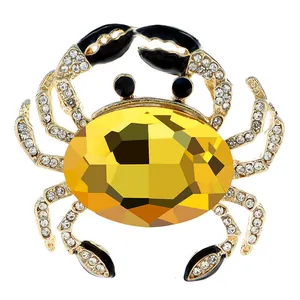 Detailed view of a gold-tone crab brooch with a large yellow faceted crystal center.