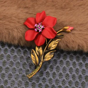 Close-up detail of a vintage red flower brooch with crystal accents and gold leaves.