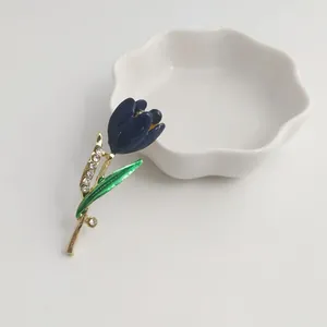 Detailed close-up of an elegant blue tulip brooch with green leaf and rhinestones