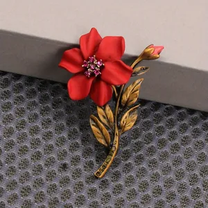 Close-up detail of a vintage red flower brooch featuring gold leaves and pink crystals