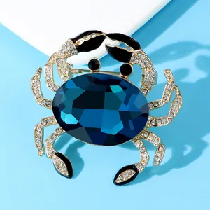 Close-up of a luxury crab brooch with a faceted blue crystal and sparkling rhinestones