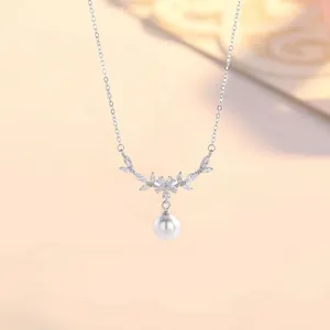 Detailed macro view of elegant silver floral necklace with sparkling CZ and white pearl pendant