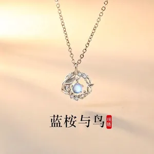 Detailed view of a silver necklace with a blue moonstone pendant and leaf accents