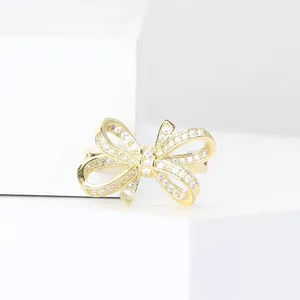 Nahaufnahme einer eleganten goldenen Schleifenbrosche mit funkelnden Kristallsteinen.