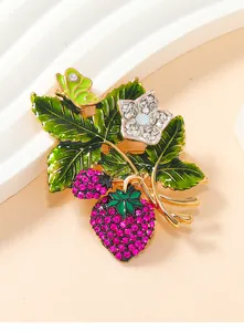 Close-up of vintage strawberry brooch with pink rhinestones and green enamel leaves