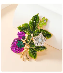 Close-up of vintage strawberry brooch with green enamel leaves and pink crystals