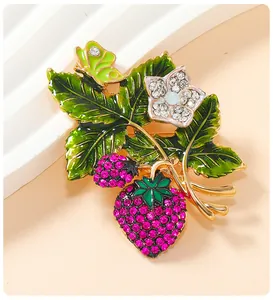 Close-up detail of a vintage strawberry brooch with pink rhinestones and green enamel leaves.
