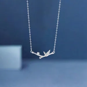 Detail of elegant bamboo branch necklace with sparkling crystals on blue background.