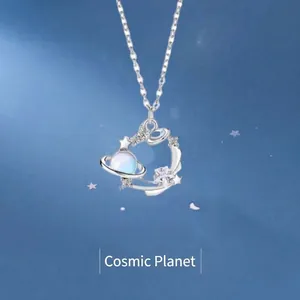 Macro detail of a silver-toned universe planet necklace featuring a glowing moonstone pendant