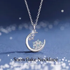 Detailed macro view of silver crescent moon necklace with blue snowflake pendant