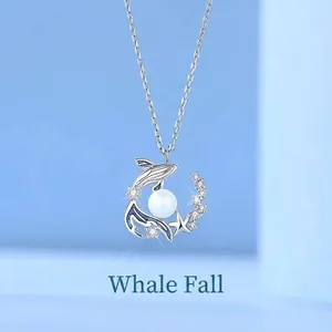 Elegant silver whale pendant necklace with a white pearl and shimmering stones.