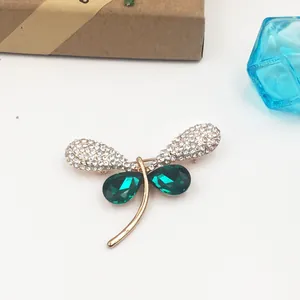 Detailed view of vintage dragonfly brooch with green teardrop stones and crystals