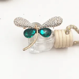 Detailed view of a vintage gold dragonfly brooch with green crystals and rhinestones.