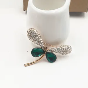 Detailed view of a vintage gold-plated dragonfly brooch with emerald green crystals