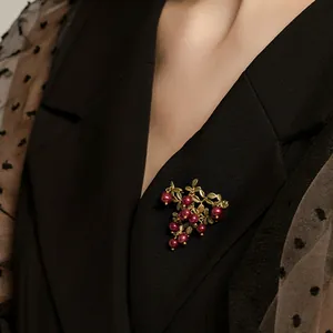 Macro detail of elegant vintage cranberry leaf brooch with red pearls pinned to a black blazer