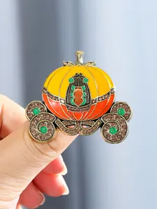 Close-up of a luxury pumpkin carriage brooch with enamel and crystals for coat decoration.