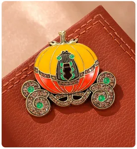 Close-up detail of luxury enamel pumpkin carriage brooch with brown rhinestones