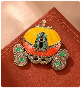 Detailed macro view showing the rhinestone and enamel work of a pumpkin carriage brooch.