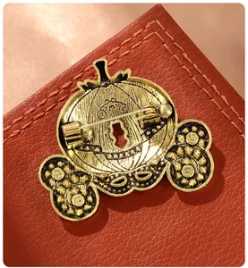 Close-up showing the sturdy back pin mechanism of a gold pumpkin carriage brooch.