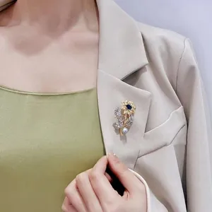 Elegant vintage sunflower brooch with blue gemstone and pearl detail on a blazer