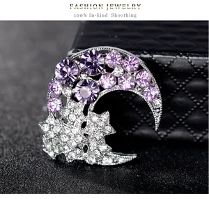 Détail d'une broche scintillante en forme de lune et d'étoile avec strass violets.