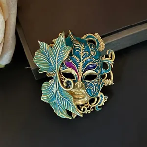 Vue macro d'une broche masque vintage plaquée or avec émail bleu sarcelle et feuille.