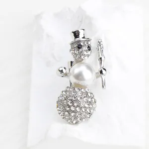 Close-up of a silver-toned snowman brooch with sparkling rhinestones and a white pearl