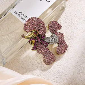 Détail d'une broche caniche scintillante en strass roses avec nœud et finition dorée.