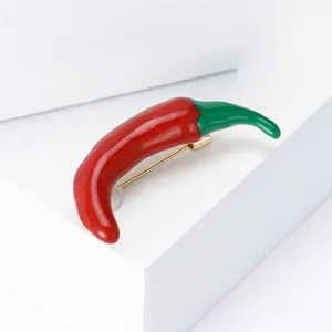 Close-up of a vibrant red enamel chili pepper brooch with a green stem design
