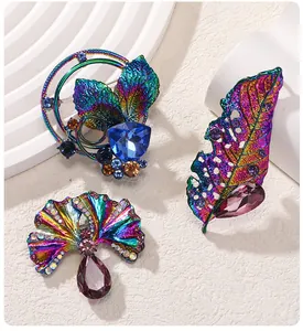 Dettaglio di spille a foglia iridescenti colorate con cristalli viola e blu scintillanti.