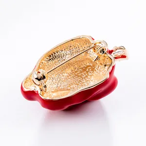 Back view of a red chili brooch with gold-plated pin and textured metal detail.