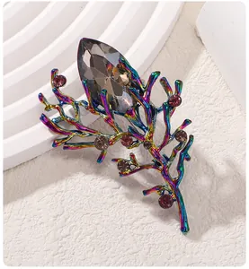 Primo piano di una spilla a forma di ramo arcobaleno con cristalli su sfondo bianco
